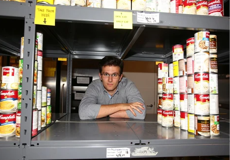 text des: Adrian leaned against a shelf at the Food Bank, surrounded by cans.