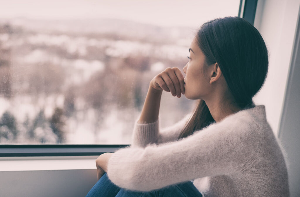 A woman staring out the window wondering if suicidal thoughts are normal and where to seek help.