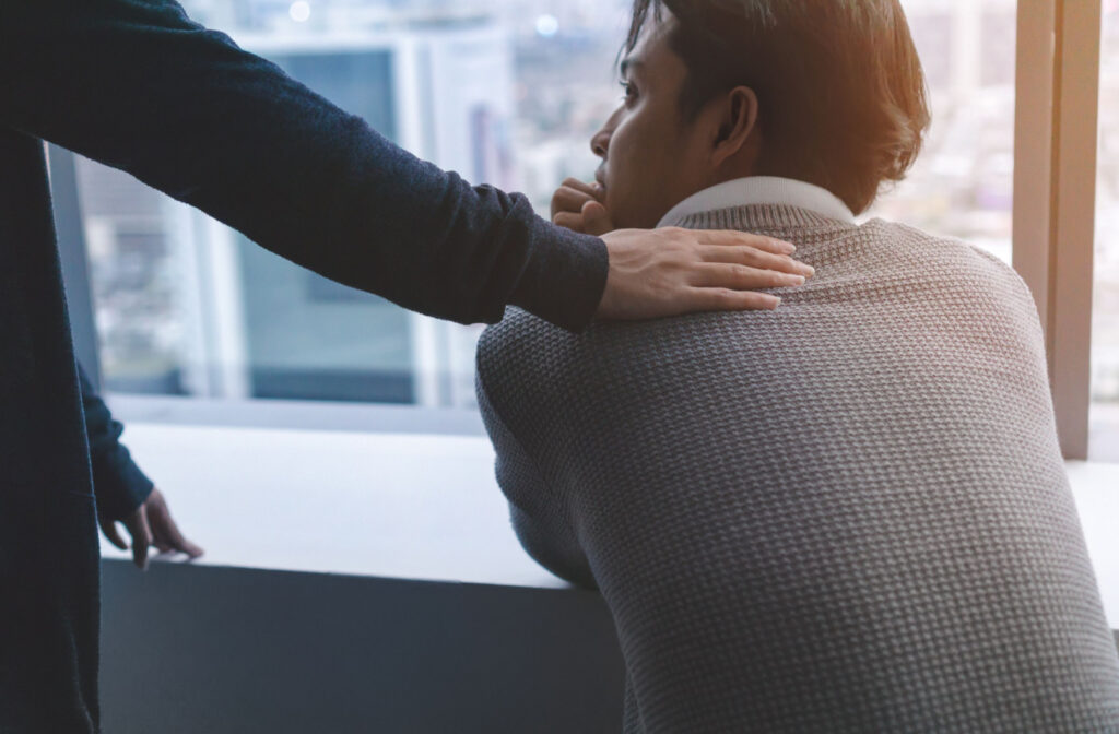 A person with their hand on a loved ones shoulder, showing care and support.