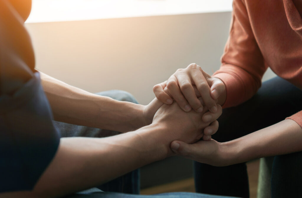 A close up of 2 people grabbing each others hands as a sign of support for mental health struggles and suicidal thoughts.
