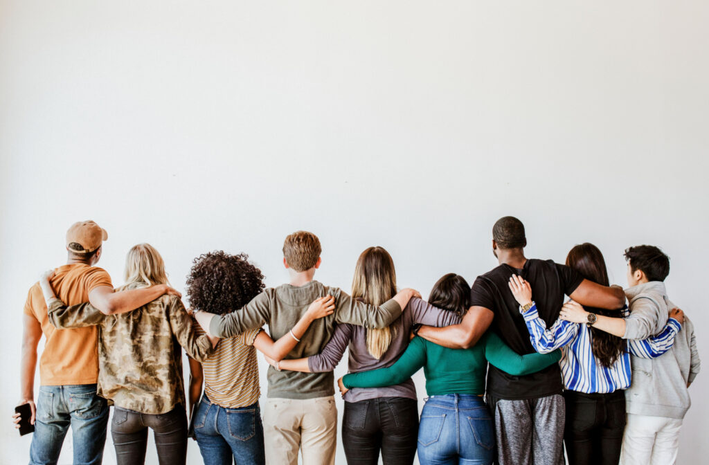 A group of people standing in a line with their arms around each other as a form of peer support.