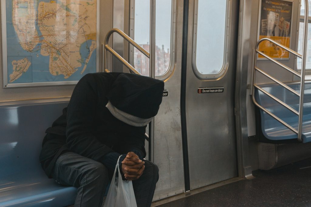 Photo of a person with their head bent down and hands clasped in a train.